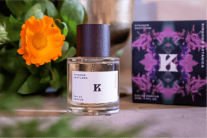 Perfume bottle with a decorative box and orange flower on a blurred background