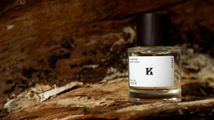 Perfume bottle of Kingdom Scotland with a backdrop of bark and woods